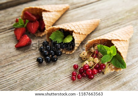 ice cream cones with berries on a wooden background