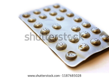 A close-up photo of push-trough pack of pills with drawn smile icons, over white background, place for text, medicine and health care concept