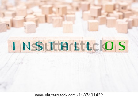 The Words Install OS Formed By Wooden Blocks On A White Table