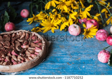 Apple pie on wooden blue rustic background. Hello autumn picture. Apples, yellow flowers and plums.