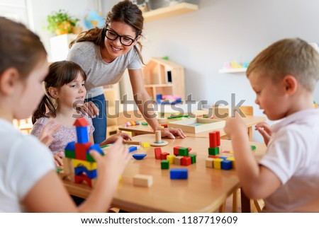 Preschool teacher with children playing with colorful wooden didactic toys at kindergarten Royalty-Free Stock Photo #1187719609