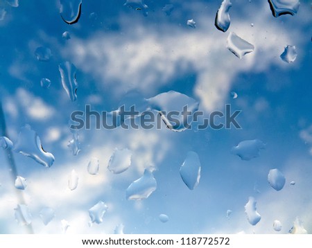 many raindrops in bad weather on a window pane. improvement in the weather. blue sky through window glass.