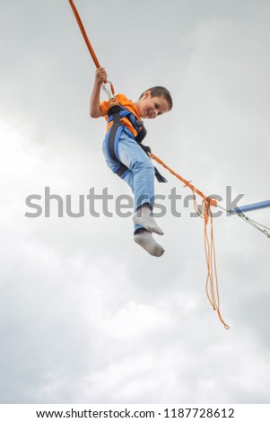 happy boy, 6 years old, jumping on a blue sky background, bungee trampoline, concept happy emotion, positive, fun