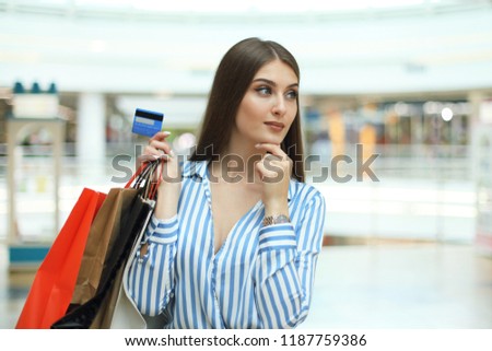 Shopper girl holding credit card and shopping bags looking up.