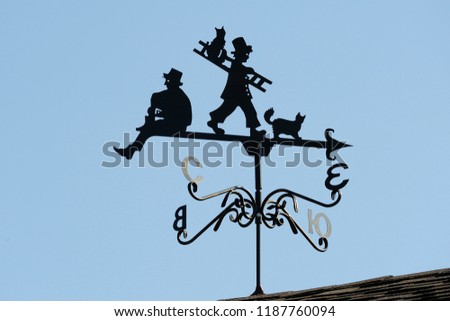 Weathervane in the form of people and cats.. A product made of metal on the roof of the house.