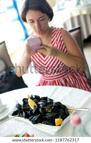 Women take pictures of boiled mussels served on the table. Albania. Adriatic coast. National food. Toned