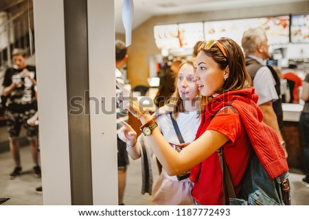 A woman orders food in the touch screen terminal with electronic menu in fast food restaurant Royalty-Free Stock Photo #1187772493