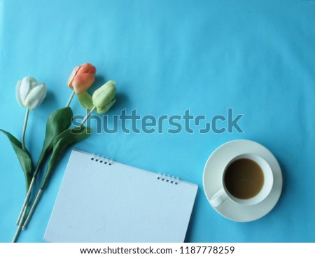 office table desk coffee notebook flower glasses on blue background top view and copy space for text