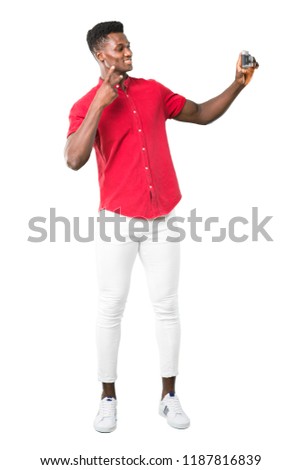 Full body of Young african american man making selfie with old camera on white background