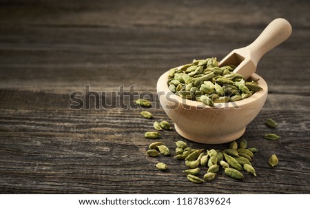 Cardamom  in a wooden scoop . Cardamom  in a wooden shovel  on a gray wooden background. Royalty-Free Stock Photo #1187839624