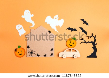 Flat lay Halloween background with cartoon house, car, pumpkins and ghosts. Space for text.