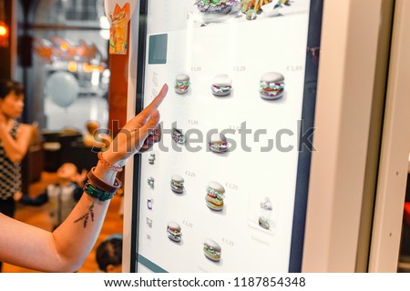 A woman orders food in the touch screen terminal with electronic menu in fast food restaurant Royalty-Free Stock Photo #1187854348