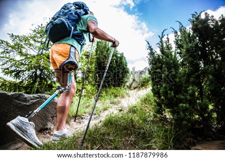 Motivated active male tourist with prosthesis going up while trying Nordic walking Royalty-Free Stock Photo #1187879986