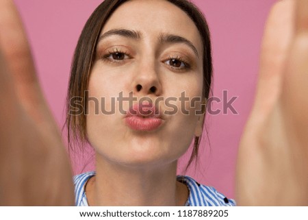 Kiss for You. Happy young brunette woman wearing elegant blue shirt smiling portrait against pink background