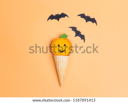 Waffle cone with funny Halloween pumpkin on a yellow background. Flat lay festive  concept. 