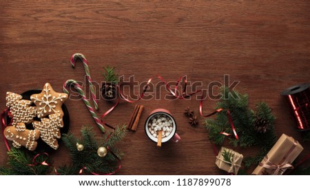 flat lay with cup of hot chocolate with marshmallows, cinnamon sticks and christmas decorations on wooden background