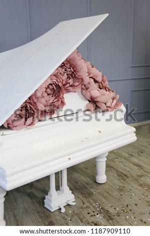 
white grand piano decorated with pink pale yellow peonies made of paper in luxury suites with gray walls 