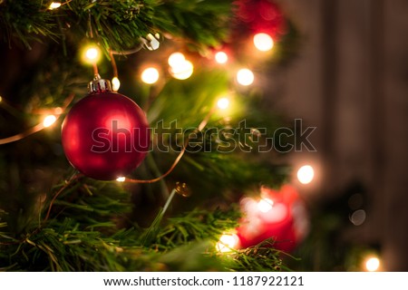 Red Christmas ball on a Christmas tree with a garland on the background of a wooden wall