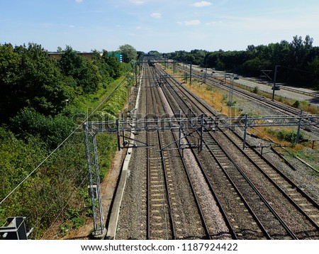 A view of train tracks and power lines from a road bridge.