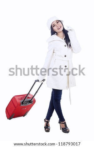 Beautiful young woman traveler with red suitcase for winter holidays