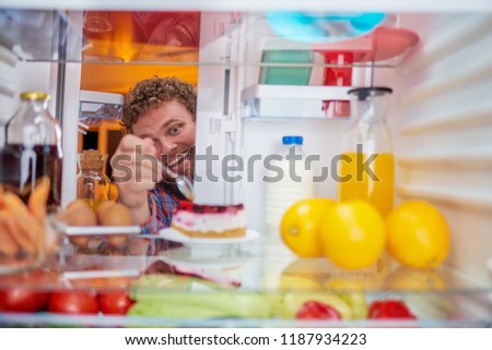 Man taking cheesecake from fridge. Picture taken form inside of frigde.