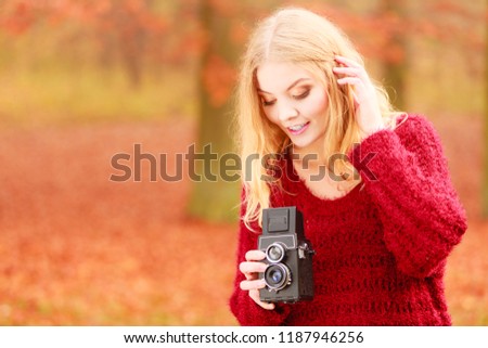 Portrait of pretty woman in fall forest park with old vintage camera. Gorgeous young girl passionate photographer. Autumn winter photography.