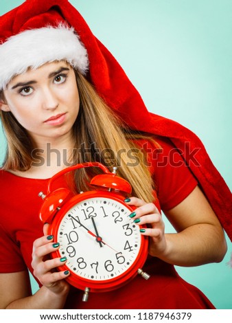Xmas, seasonal clothing, christmas time concept. Sad woman wearing Santa Claus helper costume holding big red clock, waiting for celebration