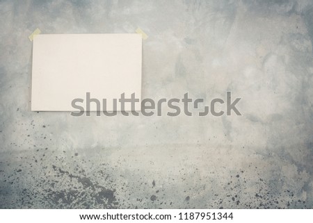 Large paper poster blank hanging on retro old grunge concrete textured wall background. Vintage style filtered photo