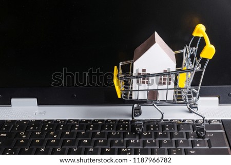 Shopping cart full of paper hose model on laptop notebook.Online shopping concept.Real estate concept, New house concept.Buying a house