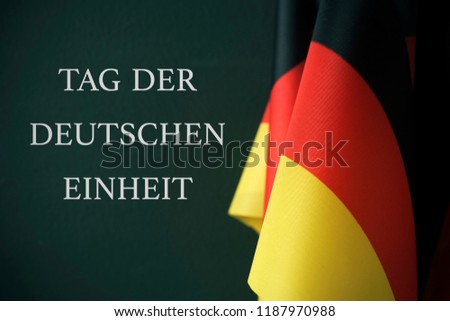some flags of Germany and the text Tag der Deutschen Einheit, Day of German Unity written in German, against a dark green background Royalty-Free Stock Photo #1187970988