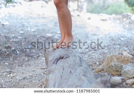 Blurry girl wearing a dress
walking barefoot on a large stump