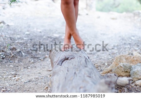 Blurry foot, girl standing cross legged
on a large stump