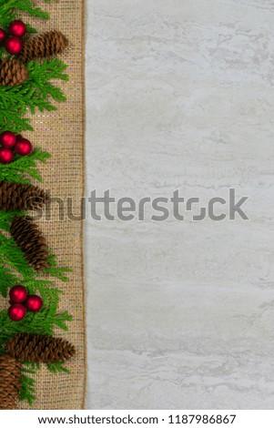 Cedar with pine cones and red berries on a burlap ribbon down the left side with copy space
