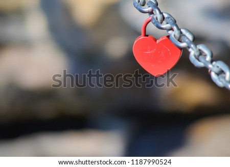 Red padlock in shape of heart hanging on a chain