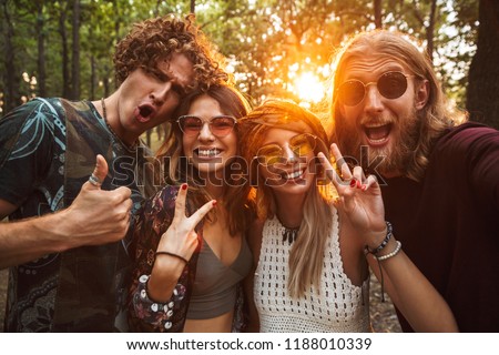 Photo of happy hippie people men and women smiling and taking selfie in forest