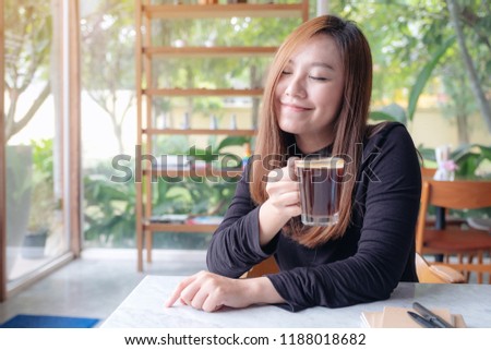 Closeup image of Asian woman smelling and drinking hot coffee with feeling good in cafe