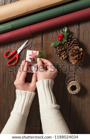 Top view of female hands wrapping Christmas presents on wooden table background