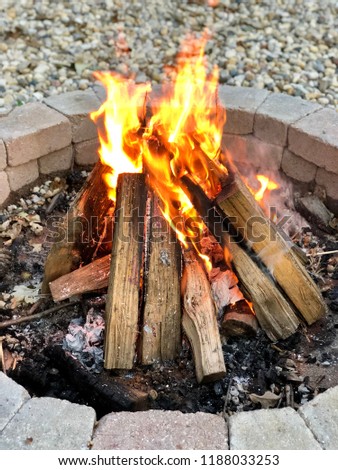 Picture of a bonfire, burning firewood brightly, in a brick firepit on a summer evening/night.