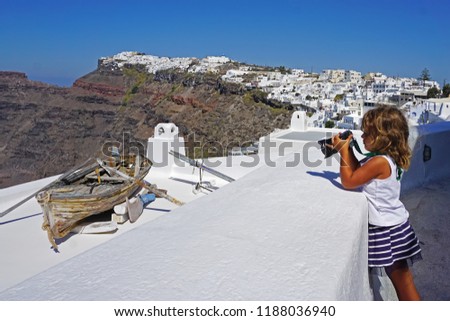 little girl takes pictures of beautiful views of Santorini, Greece