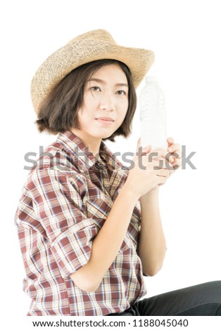 Young pretty woman in a cowboy hat and plaid shirt holding a water bottle isolated on white background