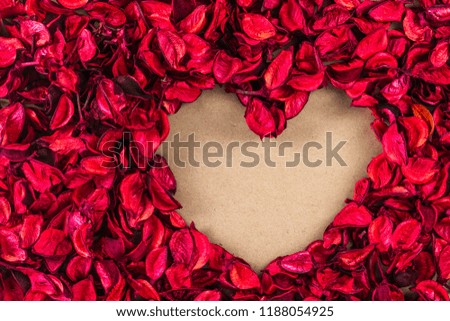 heart shape made of red dry petal on craft paper, top view