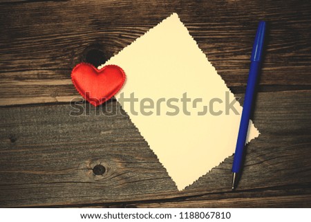 greeting card with heart nad pen on the aged wooden surface of table. vintage style. retro style filter