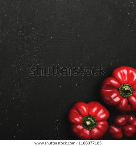 Top view of three red peppers on black background with space for text