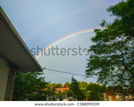 Clear rainbow over small town and buildings of Tineo, Asturias, Spain