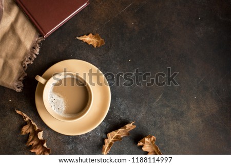 Cup of cocoa, book and autumn leaves on rustic brown background, top view. Seasonal cozy autumn hot drink, relax concept.