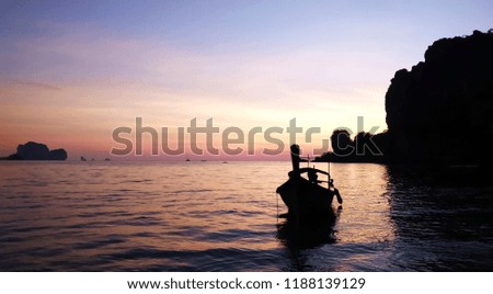 The beautiful colors of the sky and the silhouette of the boat, floating in water and the silhouette island behind. 