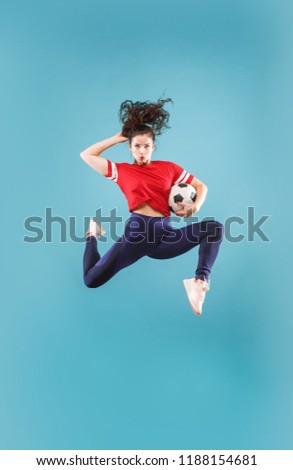 Forward to the victory.The young woman as soccer football player jumping and holding the ball at studio on pink background. Football fan and world championship concept. Human emotions concepts