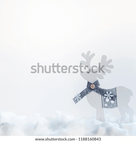 A square photo of white Christmas copy space with snow and wooden reindeer in a scarf
