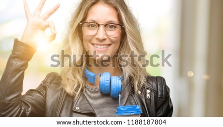Young student woman with headphones doing ok sign gesture with both hands expressing meditation and relaxation