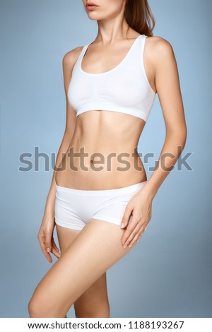 Closeup of female with fit slim body in panties and bra suffering from pain and holding her hand on the hip. Joint or muscle aches issues concept